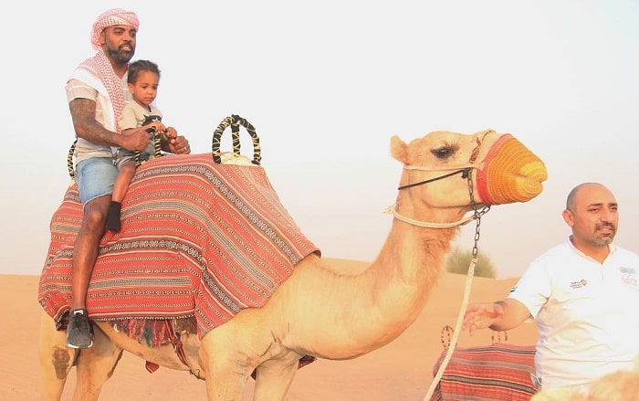 Ace wells riding in camel with his dad in Dubai.